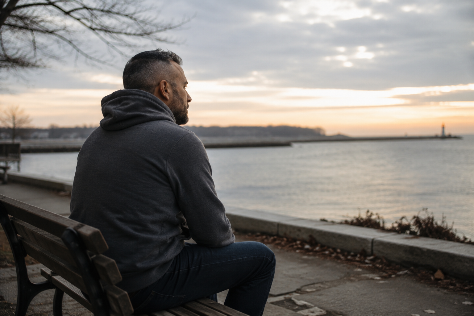 Man sitting quietly on a waterfront bench at sunset reflecting on resilience, neurological hardship, and life with epilepsy